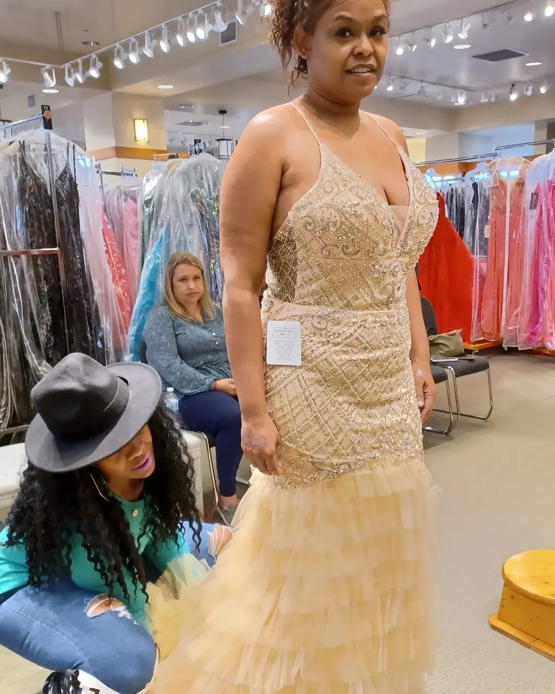 Stylist adjusting a beaded champagne gown during a fitting